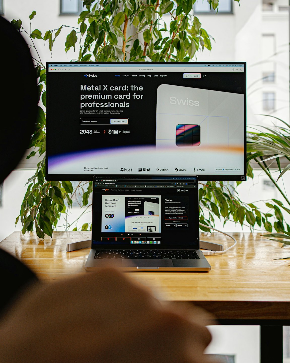 Designer lavora a un laptop e un monitor con il design di un sito web.